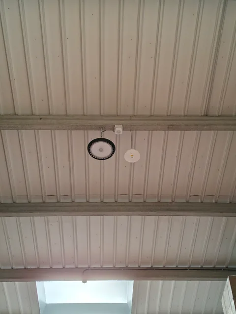 Punto de acceso Wi-Fi instalado junto a una luminaria en la estructura de una nave